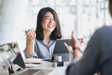 Smiling woman at a desk holding a pen